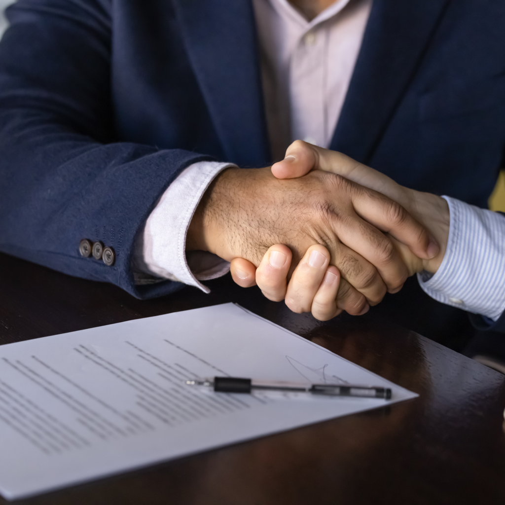 two men signing agreement and shaking hands